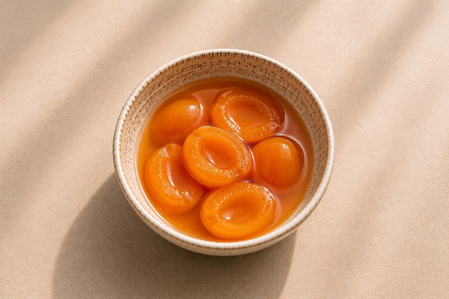 Apricot halves in light syrup in a ceramic bowl.