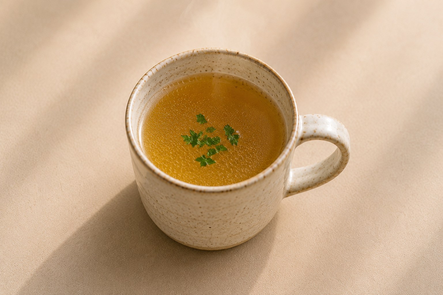 Hot chicken broth in a ceramic mug with a little parsley.