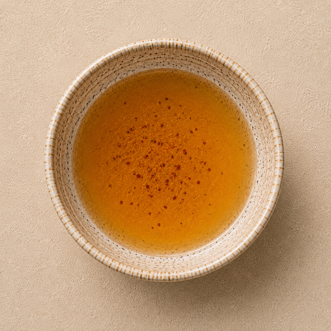 Clear golden chicken dripping sauce in a ceramic bowl.