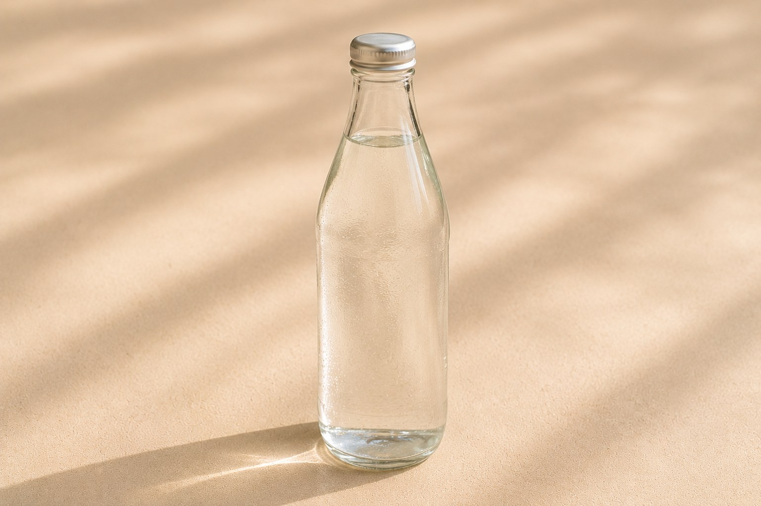 A clear bottle of still water on a beige surface.